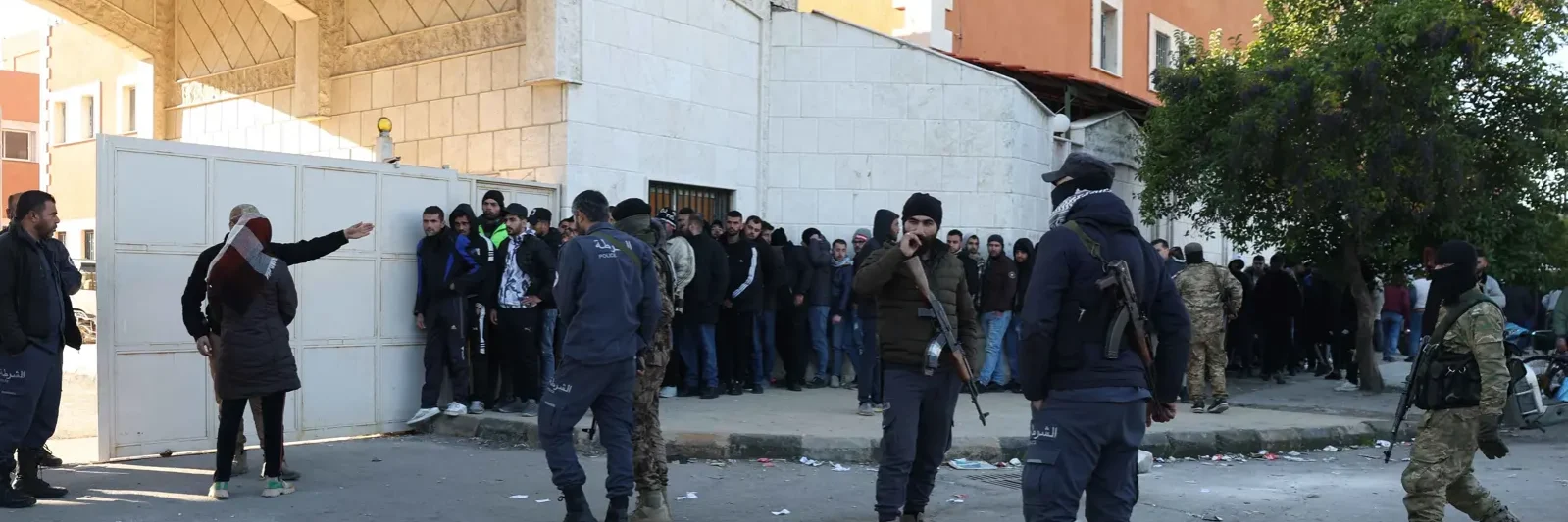 مسلحون سوريون يقفون قرب طابور من المدنيين